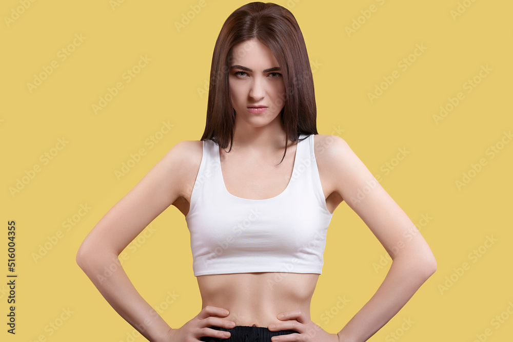 Portrait of an attractive coquettish cute angry girl in a white top on a yellow background Portrait of an attractive coquettish cute angry girl in a white top on a yellow background