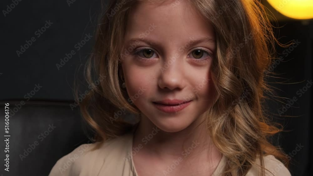 The little girl is surprised. Close-up portrait in the studio on a dark background. The little girl is surprised. Close-up portrait in the studio on a dark background.