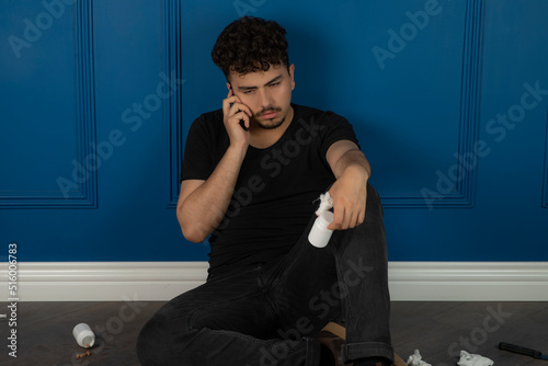 Young boy holding pills and talk on this phone for the last time.