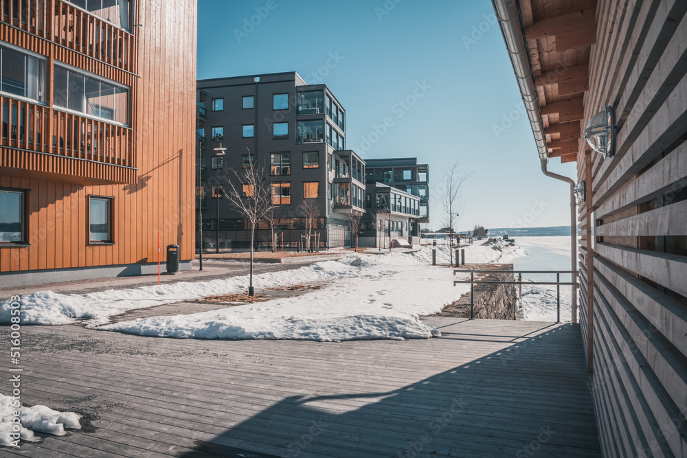 March in Östersund, Sweden - Wooden buildings of new city quarter called Storsjö Strand during spring winter under blue sky on the waterfront to Lake Storsjön.