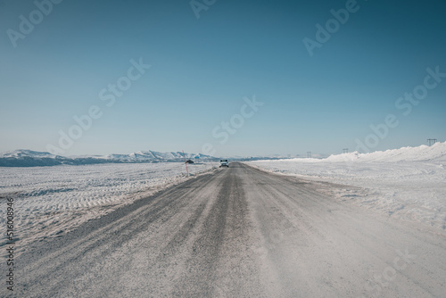 Road trip on Flatruet - Sweden's highest country road to mountain. Winter times on gravel road. Clouds of dust while car passes by rapidly.