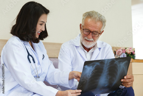 expertise senior surgical looking at x-ray film to give consult and discuss for surgery treatment the patient with young asian woman doctor in the hospital. Medical and healthcare concept..