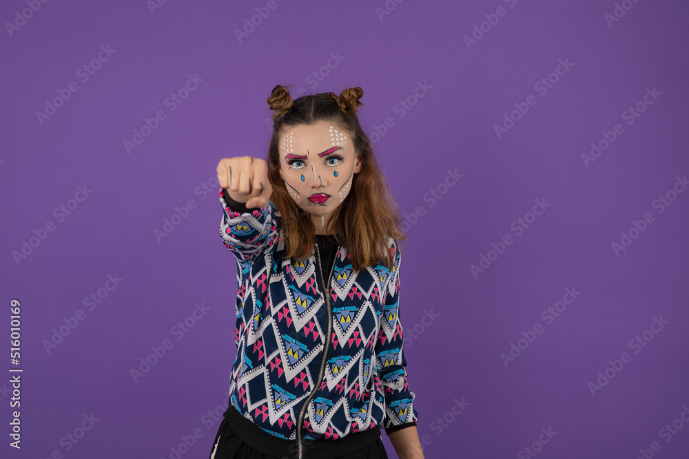 Annoyed young girl with fantasy make up showing her fist to the camera Annoyed young girl with fantasy make up showing her fist to the camera