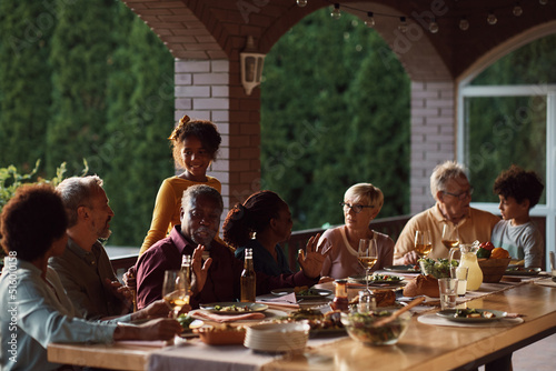 Senior black man enjoys with his multiracial family at dining table on patio.