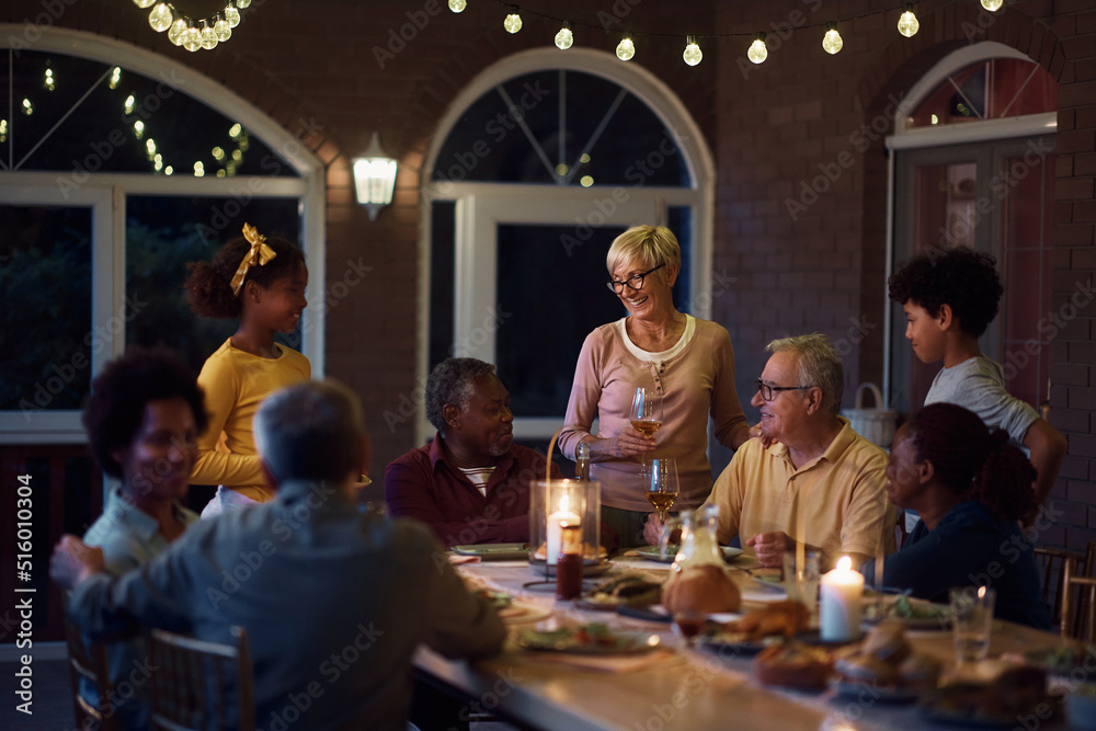 Happy multiracial people enjoying in family gathering at dining table on patio.
