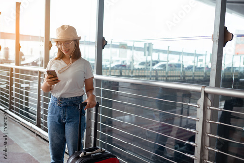 Traveler with suitcase in airport concept.Young girl using smartphone with carrying luggage and passenger for tour travel booking ticket flight at international vacation, rest and relaxation.