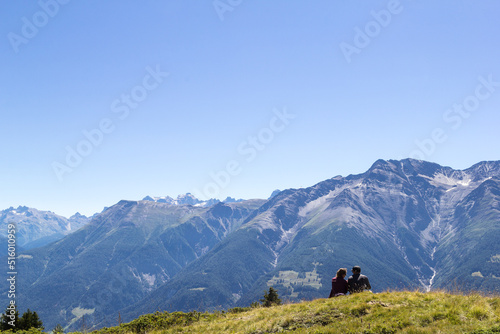 Two trekking people sitting on Alps mountains under the blue sky - copy space