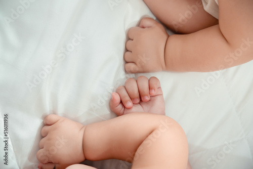 Closeup hands of newborn twin baby or cute little lying on a white bed at home. Infant child portrait happy concept, Healthy childcare in the morning.