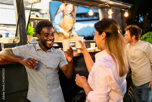 Happy multiracial friends having fun drinking beer in a street food truck market photo