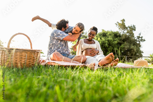 Happy multiracial family having fun together while doing picnic in the park