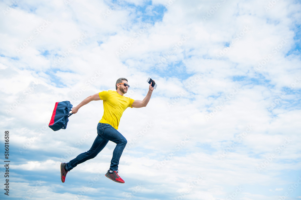 Energetic guy running with travel bag midair sky background, copy space Energetic guy running with travel bag midair sky background, copy space