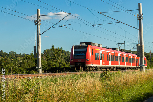 Ein Personenzug auf Gleis mit elektrischer Oberleitung