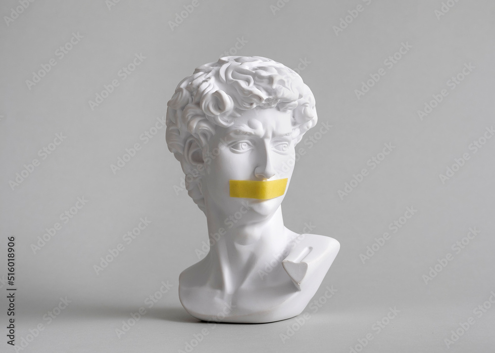 Michelangelo's David head bust in duct tape sealed mouth. Minimal concept  on gray background censorship of freedom of speech and restrictions of  thought and word. Fight for your rights. Photos