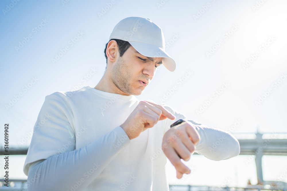 Uses a fitness watch tracker bracelet on the arm of a sporty man, fitness training on the street, measuring pulse and calories Uses a fitness watch tracker bracelet on the arm of a sporty man, fitness training on the street, measuring pulse and calories