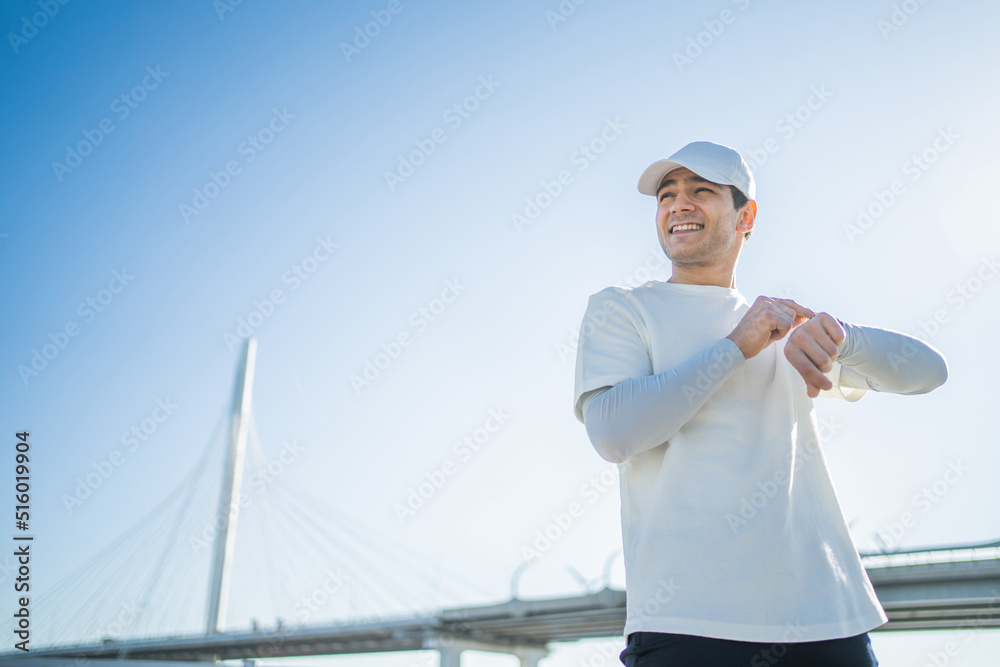 Uses a fitness watch tracker bracelet on the arm of a sporty man, fitness training on the street, measuring pulse and calories Uses a fitness watch tracker bracelet on the arm of a sporty man, fitness training on the street, measuring pulse and calories