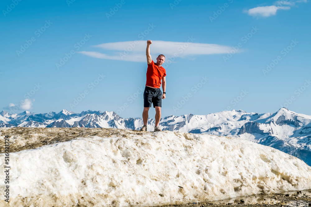 A happy man in summer clothes poses on the highest point of Rosa Peak Mountain in the Sochi resort town of Rosa Khutor.