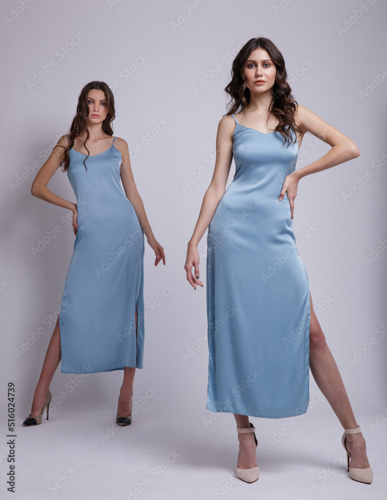 Two fashion models in same looks, outfits. Pretty sky blue dress. Beautiful young woman. Girls posing on white studio background Two fashion models in same looks, outfits. Pretty sky blue dress. Beautiful young woman. Girls posing on white studio background