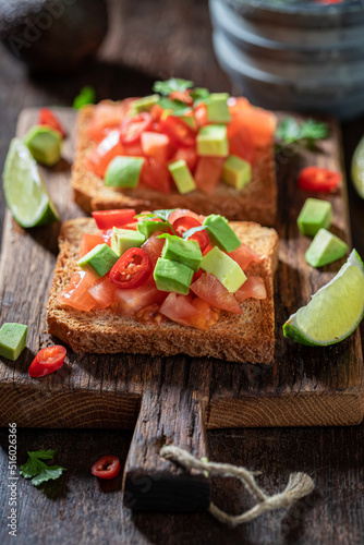 Tasty and fresh toasts with avocado, tomatoes and coriander.