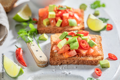 Homemade toasts made of tomatoes, avocado and chilli pepper.