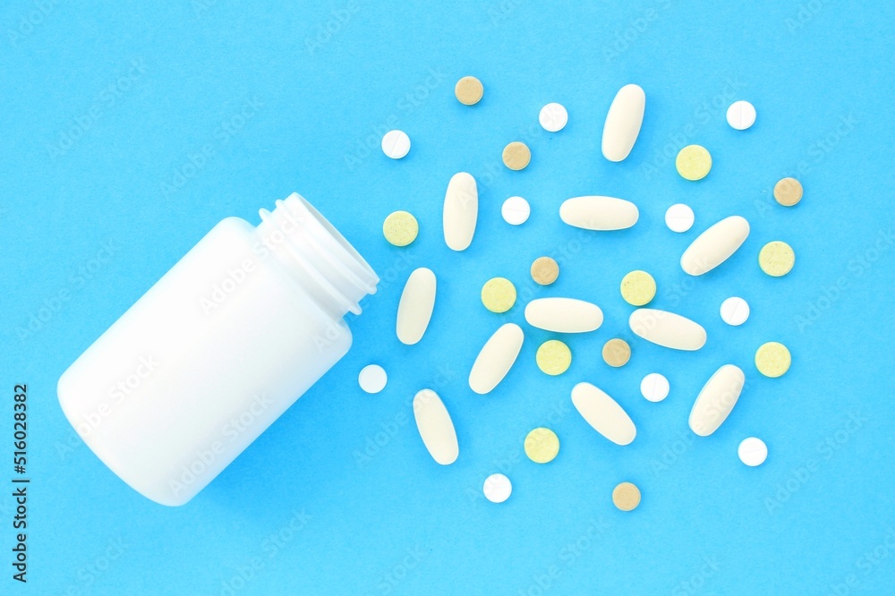 Tablets, capsule, pills and white plastic pack on blue background. Vitamin prescription supplement, drugs, Pharmaceutical medicine health therapy idea. Suicide abuse overdose concept. Doping steroid Tablets, capsule, pills and white plastic pack on blue background. Vitamin prescription supplement, drugs, Pharmaceutical medicine health therapy idea. Suicide abuse overdose concept. Doping steroid