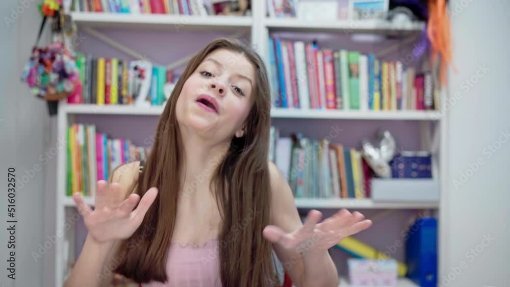 The young brunette gesticulates and sings while looking directly into the camera. The young brunette gesticulates and sings while looking directly into the camera.
