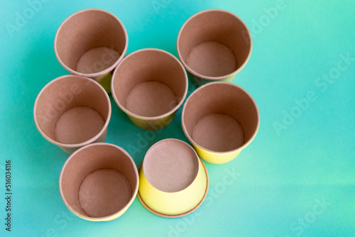 Pile of paper coffee cups lighted with yellow color. Soft selective focus, blurred. Blue background