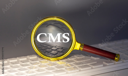 CMS text on magnifier on a keyboard, business concept