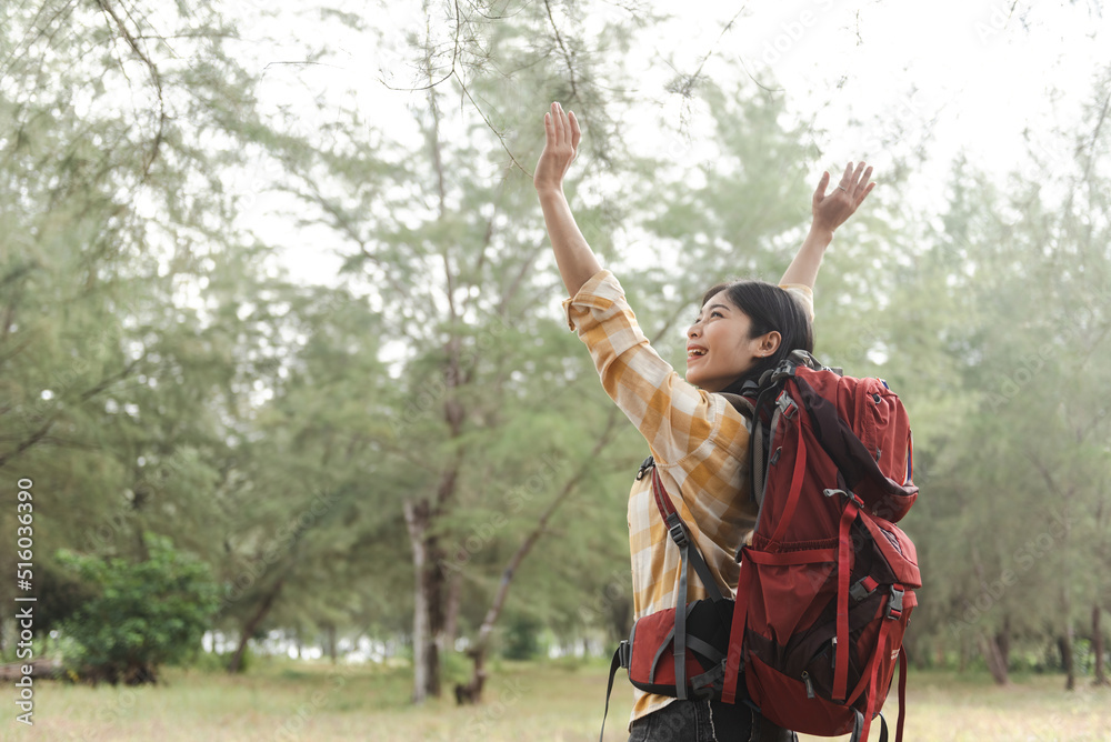 Outdoor tourism concept, beautiful Asian female backpacker raising her hand is happy.
