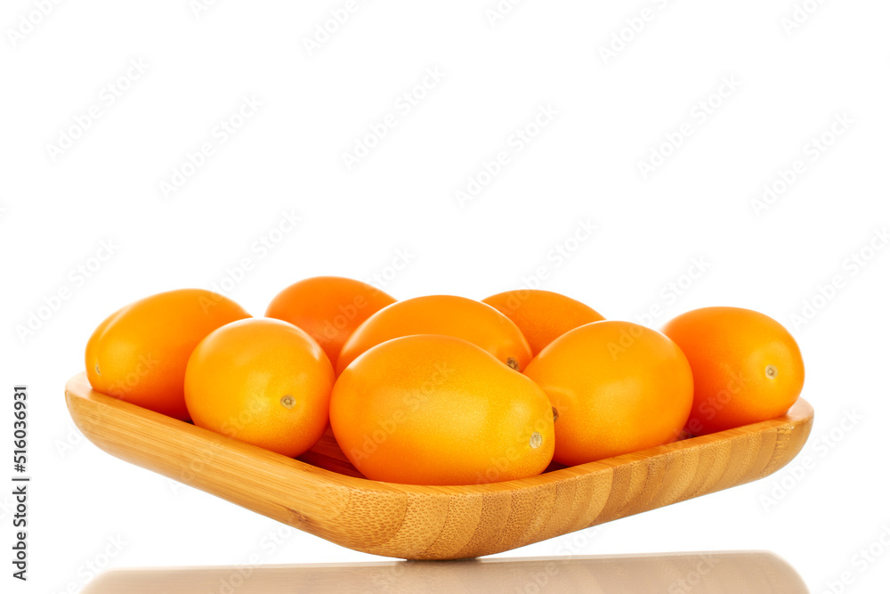 Several ripe yellow tomatoes on a bamboo plate, close-up, isolated on a white background.