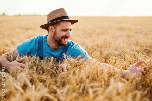 Young farmer enjoying and working in wheat field in warm sunny day.