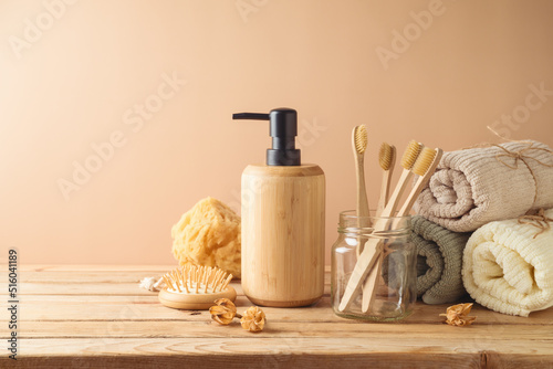 Eco friendly toothbrush, towel and body care products on wooden table over beige background