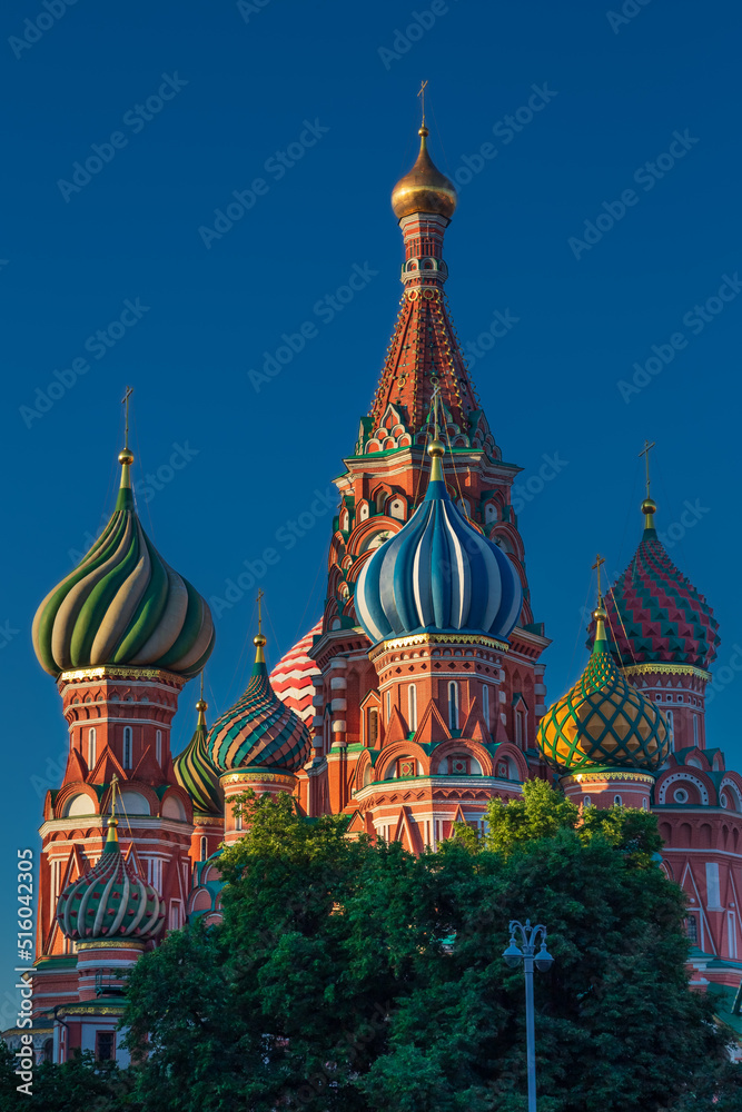 Colorful domes of St. Basil's Cathedral at sunrise against vivid blue sky, Moscow, Russia