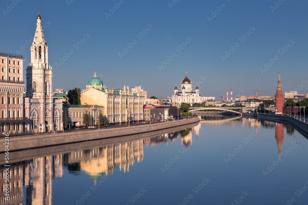 City center skyline with old buildings along river banks reflected in still water, Moscow, Russia