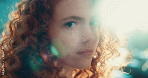 Face young sunshine woman with red hair turning look at camera stand in the city streets. Beautiful town at sunlight. Feel happy. Slow motion
