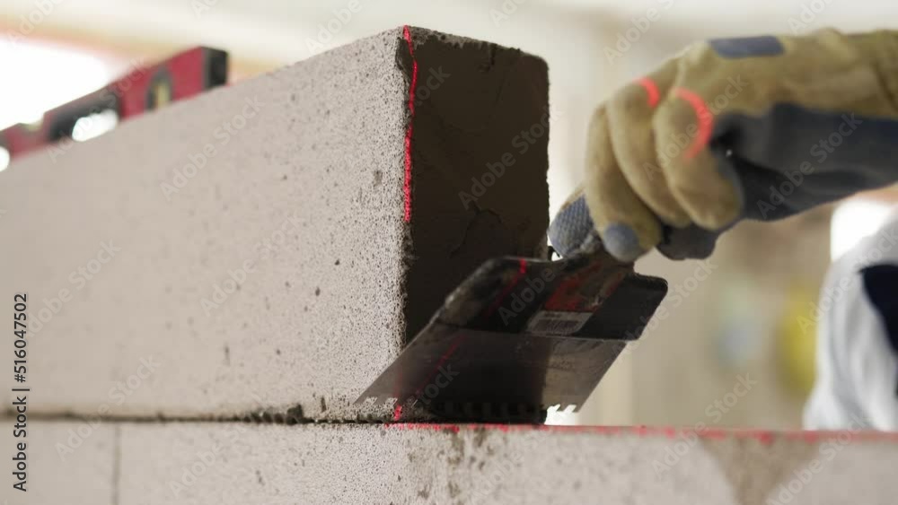 Bricklayer applies adhesive glue on autoclaved aerated concrete blocks