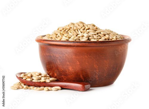 Bowl and spoon with peeled sunflower seeds on white background