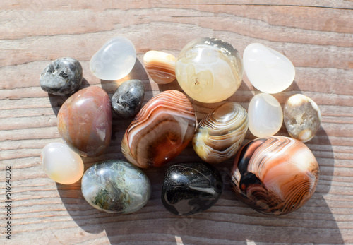 Multicolored gemstones, tumbled minerals. Bostwan agate of various sizes on a wooden background. photo