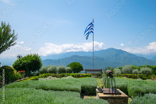 Greek flag waving in a garden of Orthodox monastery at the top of the iconic rocks of Meteora in Greece
