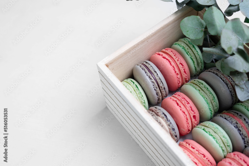 Pink, lilac and mint macaron cookies in the box with eucalyptus branches. Pink, lilac and mint macaron cookies in the box with eucalyptus branches.