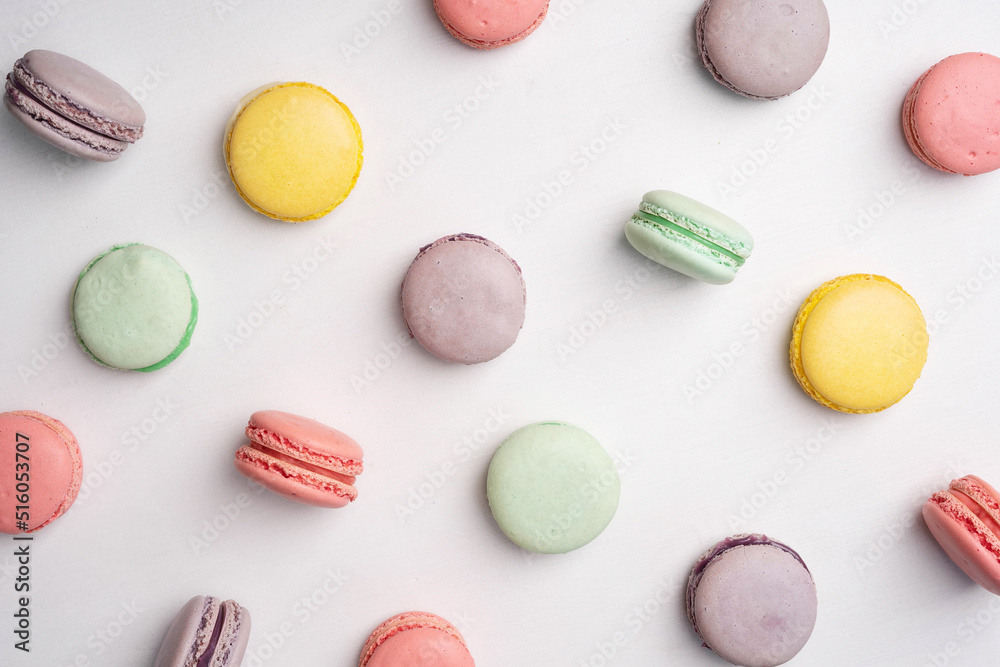 Pink, yellow, green and lilac macarons with cookies on a white background. Background with traditional french dessert.