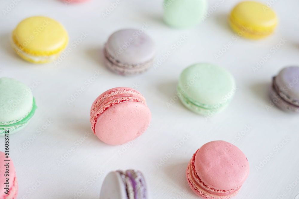 Pink, yellow, green and lilac macarons with cookies on a white background. Background with traditional french dessert. Pink, yellow, green and lilac macarons with cookies on a white background. Background with traditional french dessert.