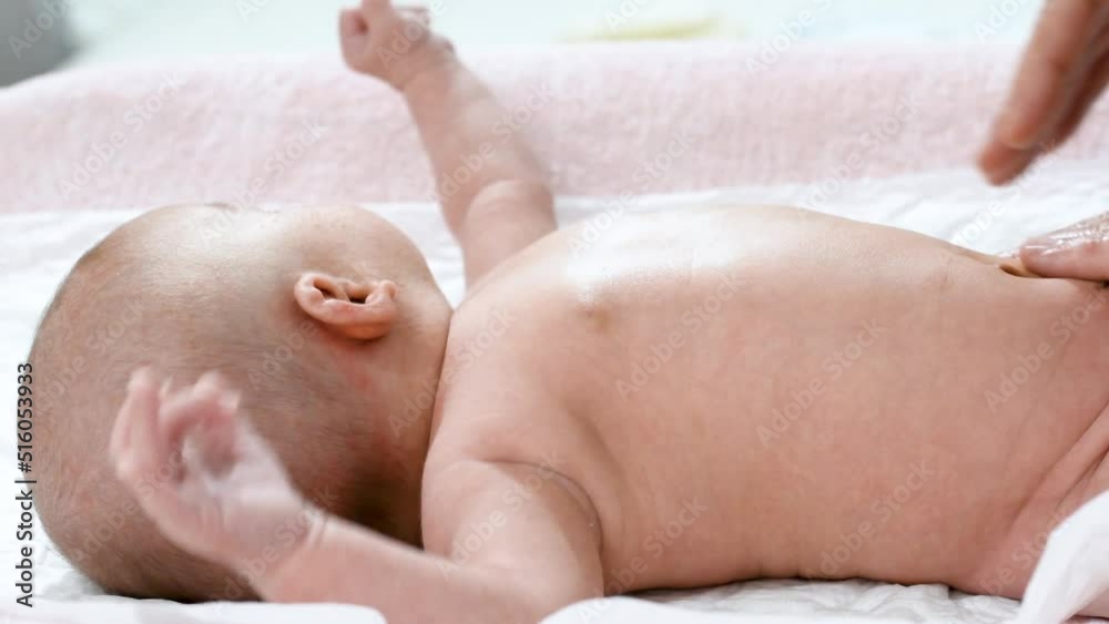 4k video of the hands of a pediatric physiotherapist performing a massage on the tummy and abdomen of a newborn baby to treat, calm and prevent infant colic