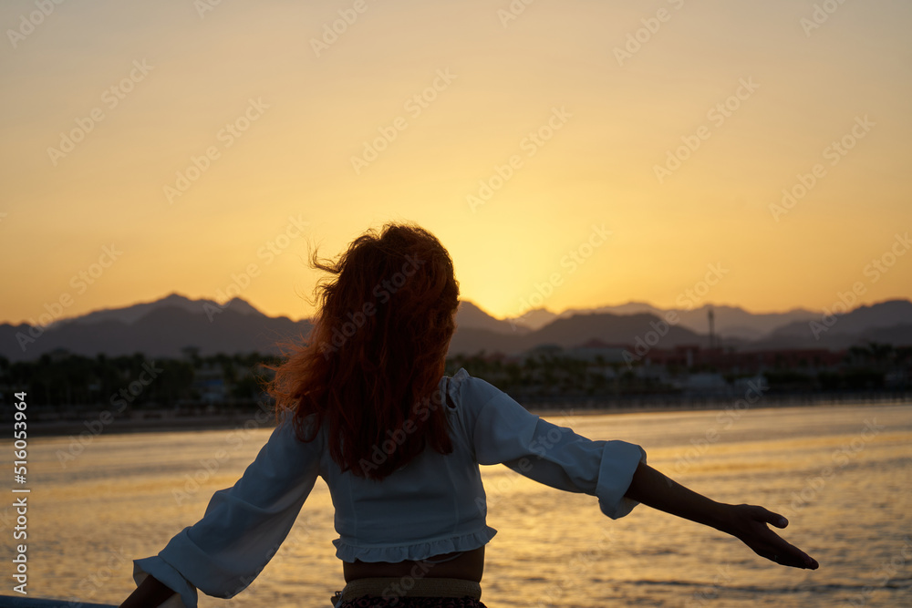Back view of travel woman with long hair on sea beach at sunset in ...