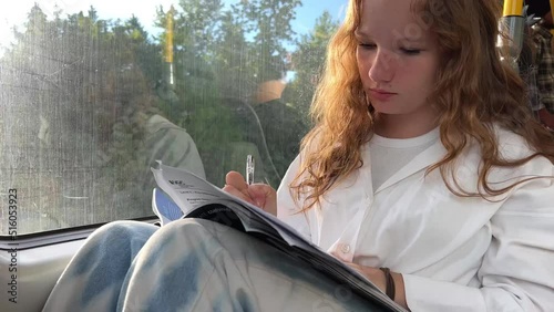 European girl in a white shirt rides in skytrain a teenage girl does her homework to hold a notebook on her knees she gets home from Vancouver Surrey nature flickers through the window and goes home photo