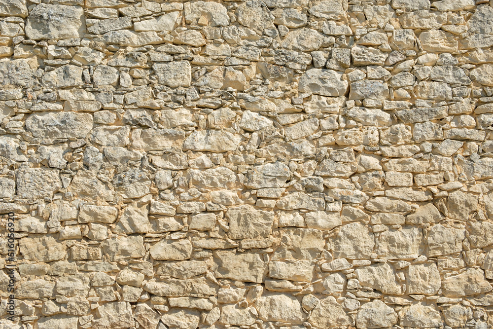Ancient stonewall with irregular pattern and grungy atmosphere from house in Carpentras, France