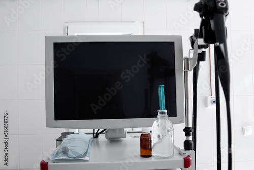 endoscope monitor without image on a white stand with accessories in the endoscopy room against a white wall