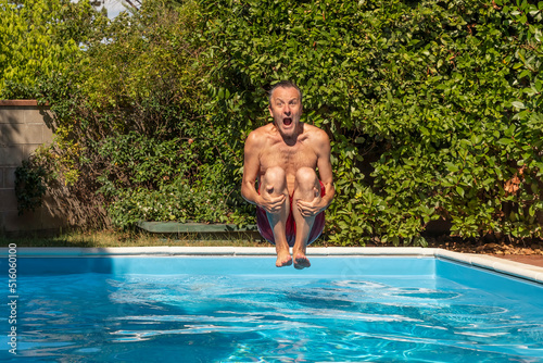 Foto A middle-aged white man dives into a pool, cannonball style, with a funny expres