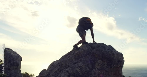 Man reaching the top of a mountain against sunset sky background with copyspace. Young fit mans fitness goals, celebrating successfully climbing a mountain and lifting his arms in a winning gesture