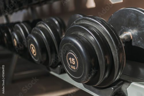 Black dumbbells on metal racks in the gym.