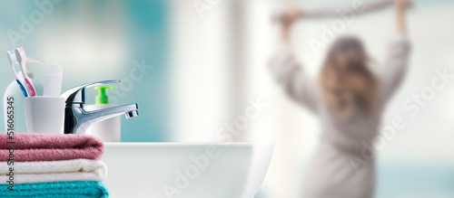 Woman in the bathroom and sink in the foreground photo